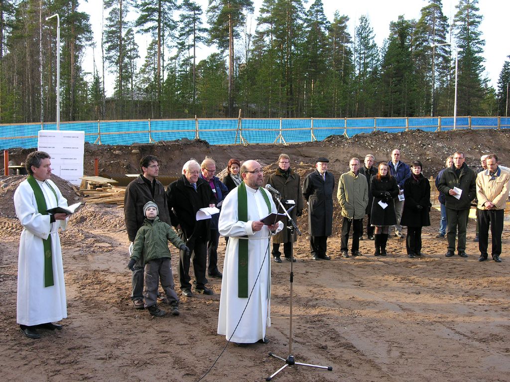 Arkistokuva Sovituksenkirkon peruskiven muurauksesta. Mikrofonin takana silloinen lääninrovasti Matti Piispanen, vasemmalla kirkkoherra Antti Lahtinen. Kuva: Juhana Säde